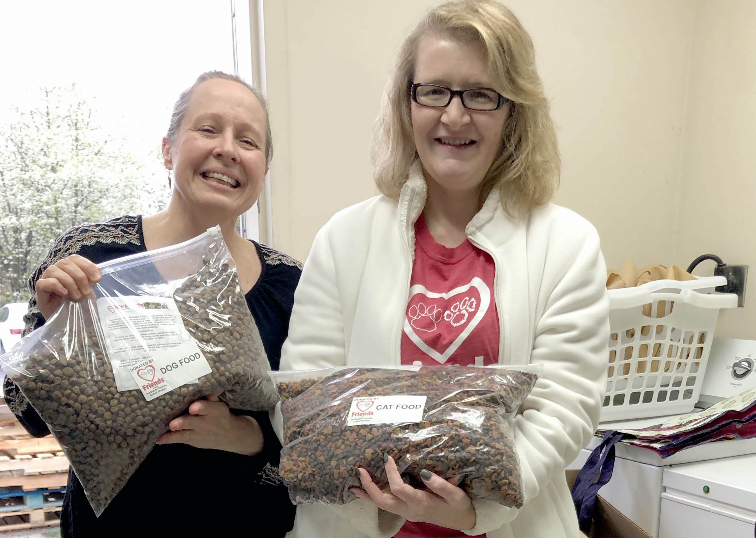 Two women with bags of dog and cat food